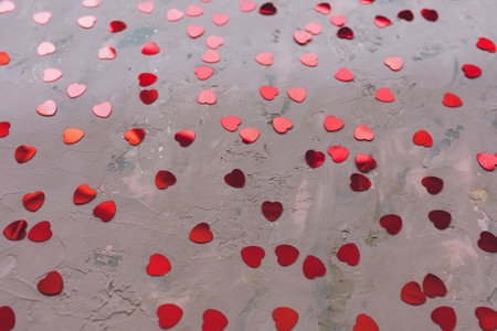 Red hearts confetti on rough concrete. Moody pink festive backround. Love, dating and St Valentines...