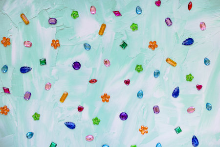 Trendy plastic colorful crystal rhinestone for sewing on green abstract background. Diy clothing...