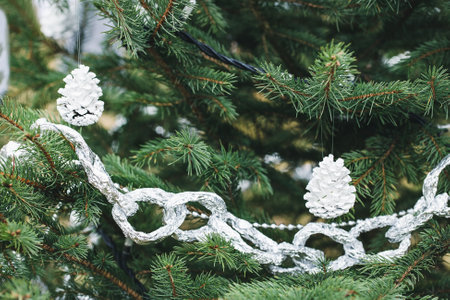 Aluminium foil and painted pine cone handmade decoration on Christmas tree outdoor. Diy creative...