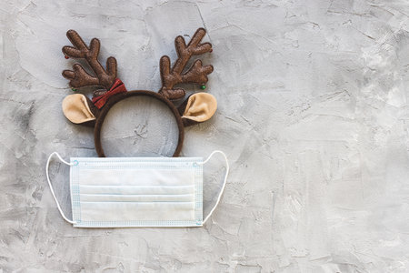 White surgical mouth mask and Christmas deer handband. Quarantine, lockdown and coronavirus Covid-19, holidays celebration, social distancing and winter season conceptの写真素材