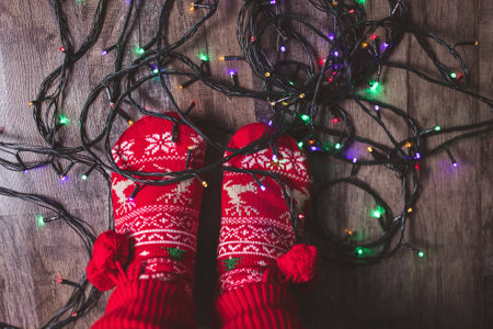 Tangled Christmas lights on the floor at feet in red Christmas socks. Winter holiday chors conceptの写真素材