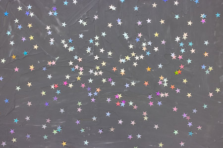 Trendy silver foil confetti stars on dark black background. Festive abstract backround. Birthday party, New Year celebration, holidays, winter and dreams concept. Selective focusの写真素材