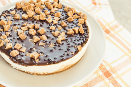 Cheesecake decorated with salted caramel pieces on light rustic background. Homemade dessert for...