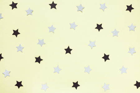 Trendy paper black and gray confetti stars on yellow background. Abstract festive backround....