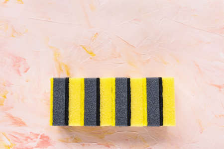 Set of new yellow and gray sponges for dishwashing on pink background. Domestic household and...