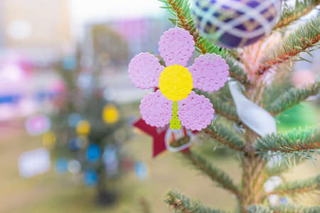 Handmade plastic pink flower decoration on Christmas tree outdoors. Creative ideas for children. Environment, recycle, reuse, upcycling and zero waste concept. Selective focus, no snow backgroundの写真素材