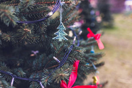 Handmade baked and painted dough Christmas decoration on a Christmas tree. Outdoor background without snow. Diy creative ideas for children. Environment concept. Selective focus, copy spaceの写真素材