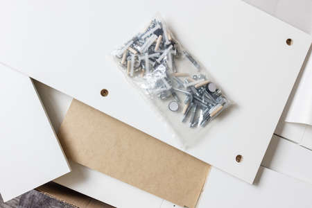 Opened box with furniture assembly parts and tools on the floor. Self assembling and DIY furniture...