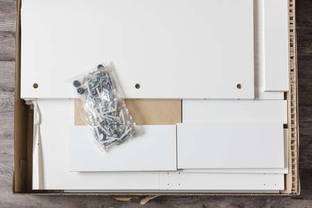 Opened box with furniture assembly parts and tools on the floor. Self assembling furniture at home concept.の写真素材