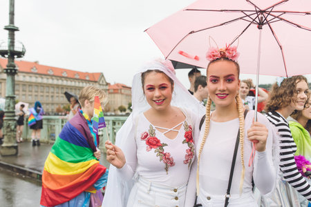 Participants of the annual Prague Gay Pride parade. Lesbian couple in a crowd, happy people marching under the rain with umbrellas. Prague, Czech Republic - August 10, 2019のeditorial素材