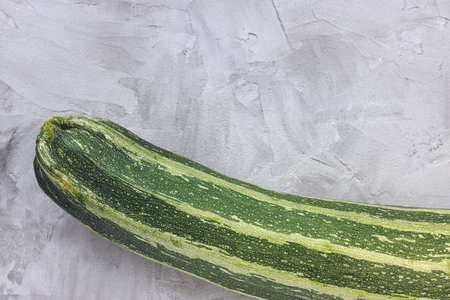 Fresh green striped zucchini on a gray backgroundの写真素材