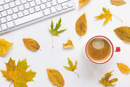 Computer keyboard, coffee and yellow fall leaves