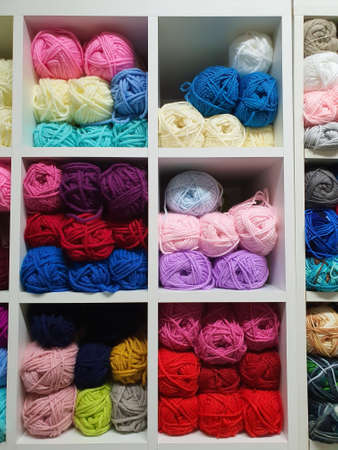 Colorful yarns or balls of wool for knitting on shelves in the haberdashery shop. Knitwork handcraft...