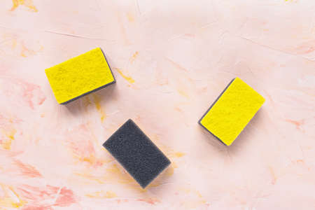 New yellow and gray sponges for dishwashing on pink background. Domestic household and cleaning...