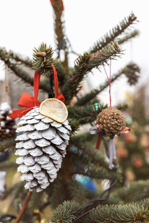 Painted white pine cone and dried lemon on Christmas tree. Diy decoration ideas for children. Environment, reuse, recycle, upcycling and zero waste concept. Selective focus, outdoor no snow backgroundの写真素材