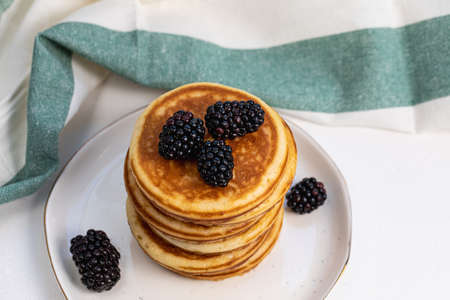 Stack of delicious pancakes on white plate with fresh blackberries. Healthy breakfast with fruits....