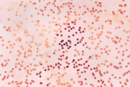 Trendy rose gold and bronze foil confetti stars on pink background. Christmas festive abstract...