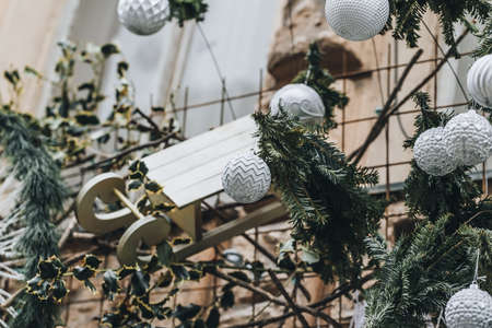 Christmas outdoor decoration on the building. Pine branches and classical Christmas balls in trendy white and silver colors. Street Christmas decoration conceptの写真素材