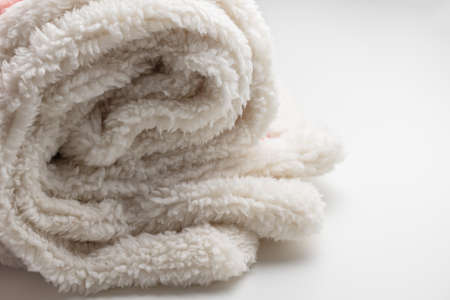 Roll up fluffy blanket on white backround. Warm cozy winter throw. Close up, selective focus, copy spaceの写真素材