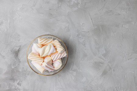 Colorful pastel marshmallow in glass bowl on gray background. Ingredient for cooking dessert and unhealthy sweets. Top view, copy spaceの写真素材