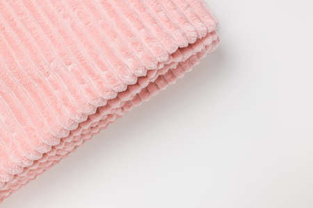 New folded soft pastel pink fleece throw fabric with lines on white background. Top view, closeup,...