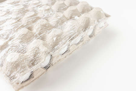 Fresh raw 30 pack of large white eggs in cardboard in foil on white background. Consumerism, egg...