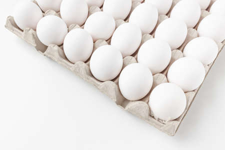 Fresh raw 30 pack of large white eggs in cardboard on white background. Consumerism, egg production, organic healthy bio product and Easter holiday concept. Top view of thirty eggs, copy spaceの写真素材