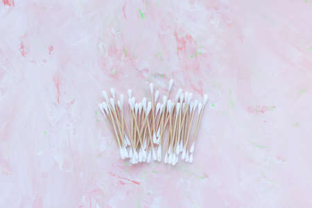 Eco-friendly bamboo cotton buds on pink background. Trendy cotton swabs, bamboo ear cleaner sticks blooming cherry blossom flowers. Flat lay, top view, copy spaceの写真素材