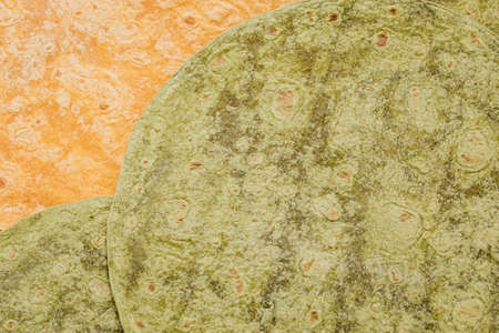 Tomato, spinach flavored wheat tortilla wraps. Spanish or Mexican circular unleavened flatbread from...
