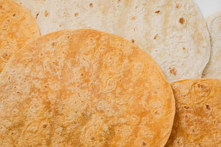 Tomato flavored and plain wheat tortilla wraps. Spanish or Mexican circular unleavened flatbread...