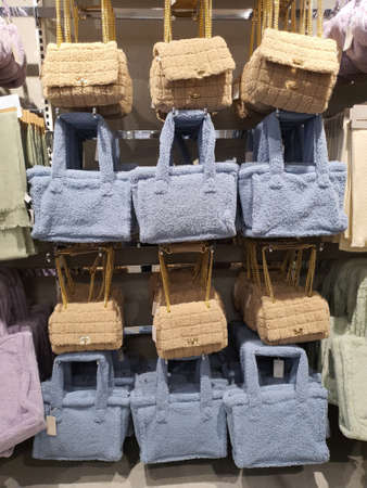 Colorful fluffy plush fabric bags hang on rack in clothing store. Trendy fall winter style. Woman...