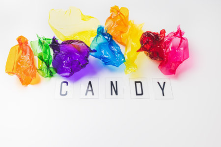 Colorful candy wrappers and text CANDY on white. Sugar sweets concept. Abstract colorful background with copy spaceの写真素材