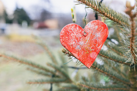 Handmade homemade baked and painted red cookie dough decorations on Christmas tree outdoor. Diy creative ideas for children. Environment concept. Selective focus, copy spaceの写真素材