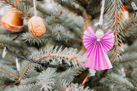 Handmade angel decoration of paper and pearl bead on Christmas tree outdoor. Diy creative ideas for children. Environment, recycle and zero waste concept. Selective focus, copy spaceの写真素材