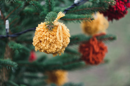 Wool handmade decoration on a Christmas tree outdoor. Diy yarn crafts creative ideas for children. Environment, recycle and zero waste concept. Selective focus.の写真素材