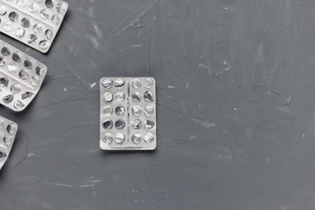 Empty blister packs of pills on gray background, supplement and medicine concept. Closeup, top view, copy spaceの写真素材