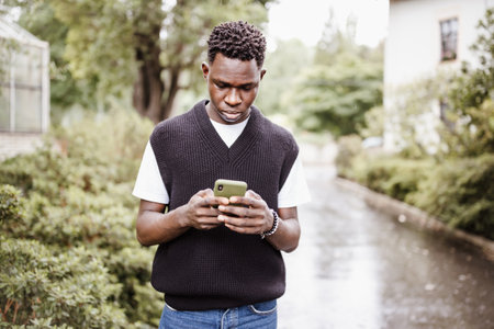 Young sad African American man in bomber jacket in park or street outdoor. Fall or spring seasonの写真素材