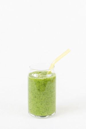 Green smoothie in glass with environmentally friendly drinking glass tube. White background. Vegan, raw, clean, healthy food. Side view, copy spaceの写真素材