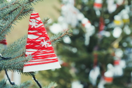 Red wool and paper handmade decoration on Christmas tree outdoor. Diy yarn craft creative ideas for children. Environment, reuse, recycle, upcycling and zero waste concept. Selective focus, copy spaceの写真素材