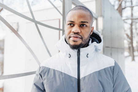 Young African man in casual white and gray clothes, sport jacket on street. Winter season urban...