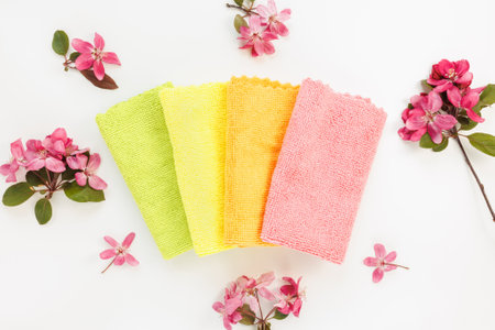 New folded microfiber cloth for cleaning on white with spring flowers background. Cleaning micro...