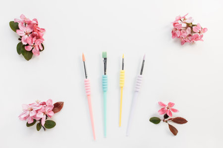 Paintbrushes for drawing, different sizes, trendy pastel colors on white with spring flowers...
