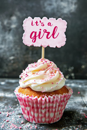 Sweet cupcake with pink sprinkles and a topper announcing Its a girlの素材