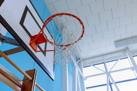 Basketball Hoop in Indoor Gymnasium with Blue Walls and Natural Light.の写真素材