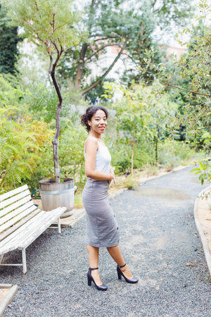 Stylish Young Woman in Modern Outfit Posing in an Urban Botanical Gardenの写真素材