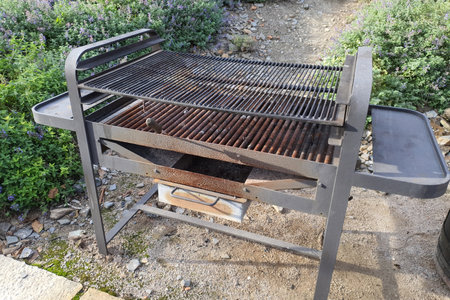 Rusty barbecue grill surrounded by flowering bushes in a gardenの写真素材