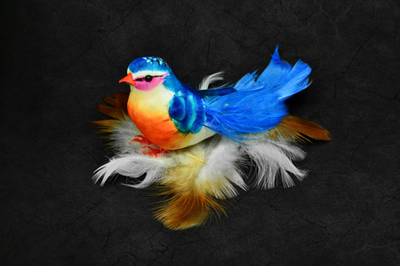 Beautiful artificial bird on natural bird feathers.の写真素材