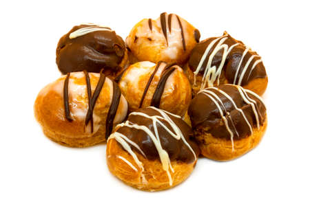 Seven profiteroles with cream and chocolate on a white background.