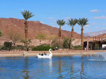 Timna Valley, Israel -  February 20, 2021: People ride boat in the form of swan on an artificial lake in the Timna Valley. The Arava Desert in Israel.のeditorial素材