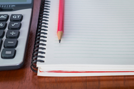 Note book with pen and a calculator on wood table, selective focusの写真素材